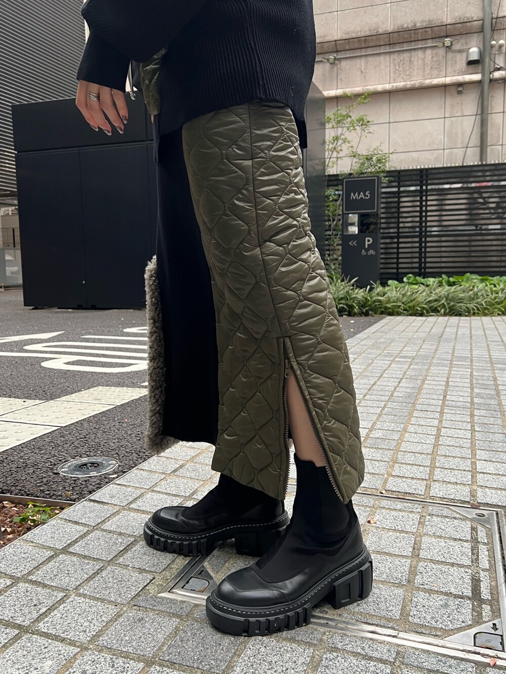 ブラック系のニット/セーター、ブラック系のスカート、ブラック系のブーツを着用したレディースの秋コーディネートの8枚目の写真