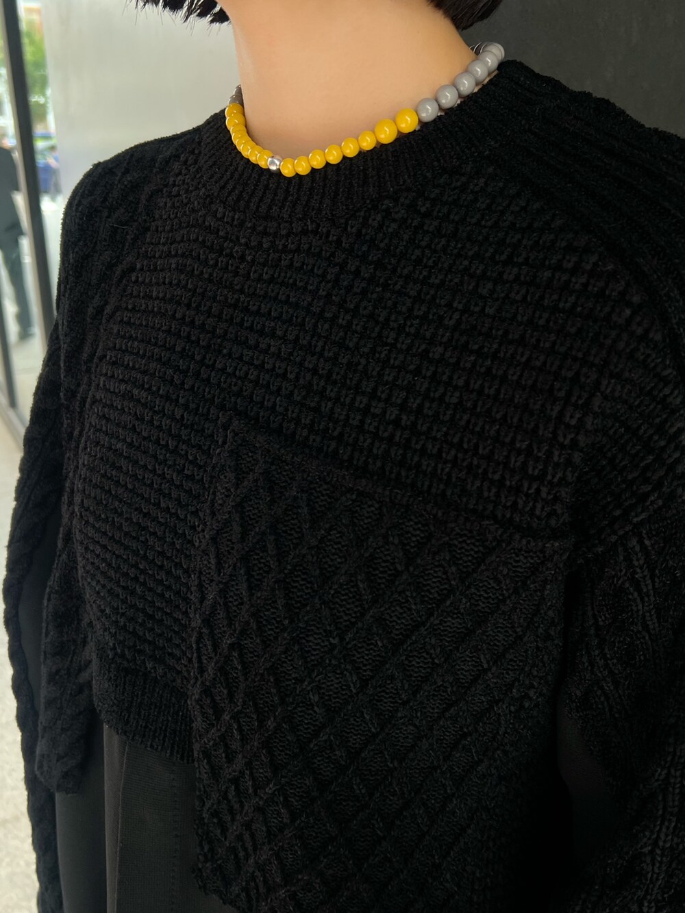 ブラック系のニット/セーター、グレー系のスカート、ブラック系のブーツを着用したレディースの秋コーディネートの6枚目の写真