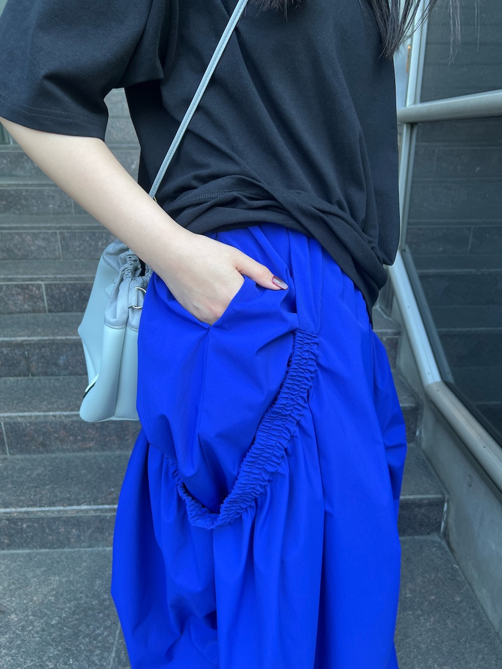 ブラック系のTシャツ/カットソー、ブルー系のスカート、グレー系のショルダーバッグを着用したレディースの夏コーディネートの7枚目の写真