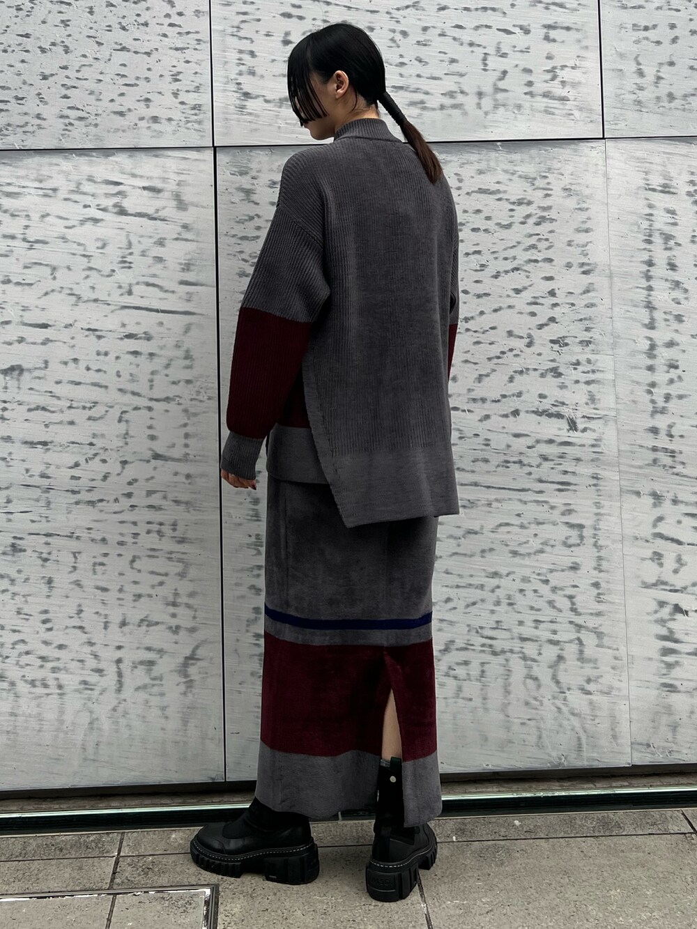 グレー系のニット/セーター、グレー系のスカート、ブラック系のブーツを着用したレディースの冬コーディネートの2枚目の写真