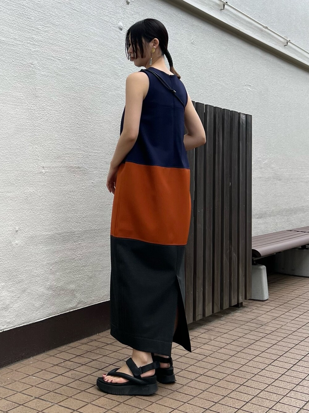 オレンジ系のワンピース、シルバー系の財布、シルバー系のイヤリングを着用したレディースの春コーディネートの2枚目の写真