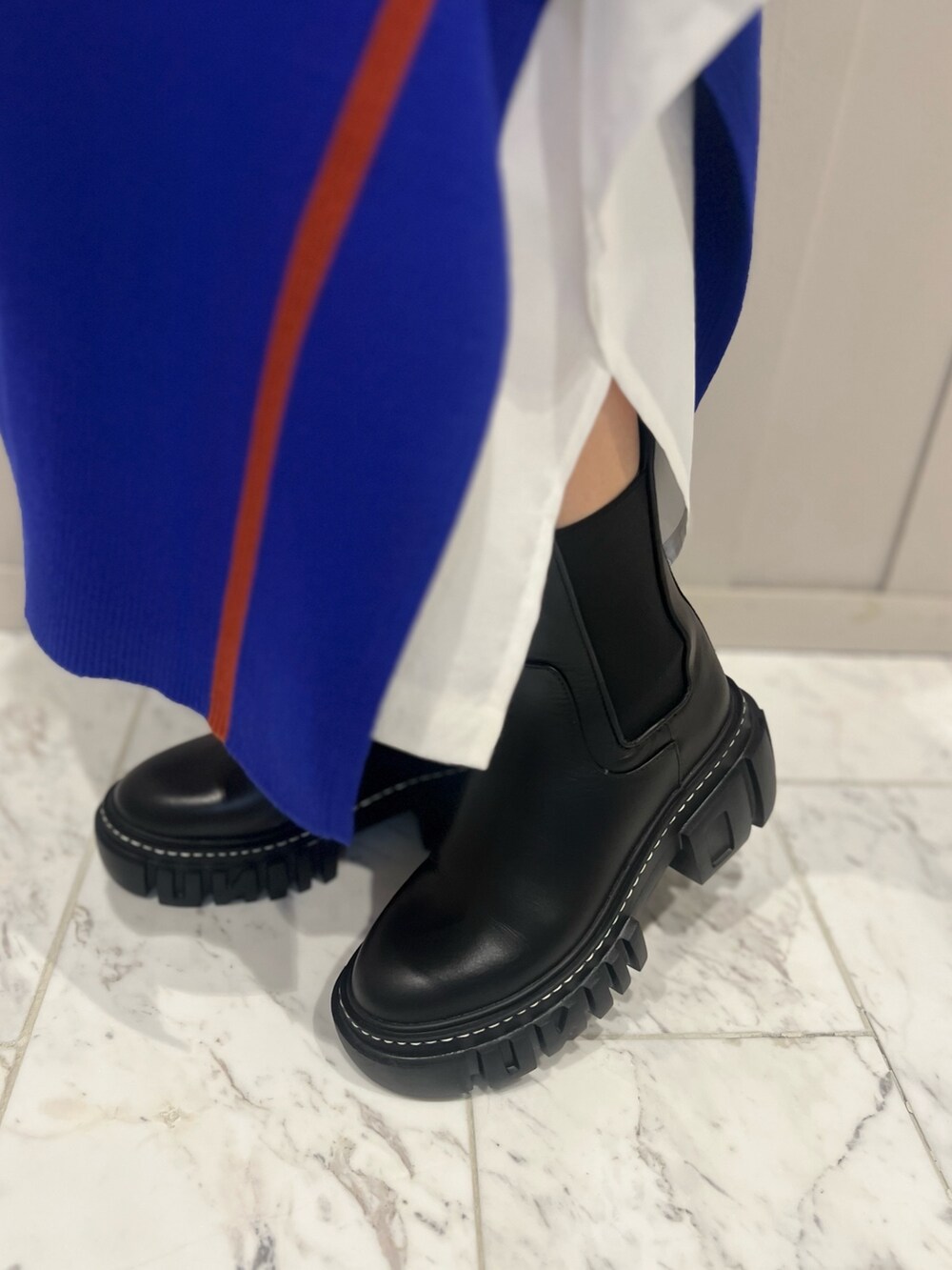 ブラック系のTシャツ/カットソー、ブラック系のショルダーバッグ、ブラック系のブーツを着用したレディースの秋コーディネートの5枚目の写真