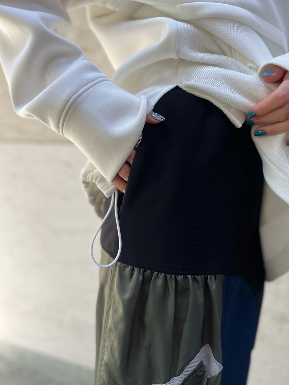 ブラック系のスカート、ホワイト系のスウェット、ブラック系のブーツを着用したレディースの秋コーディネートの8枚目の写真