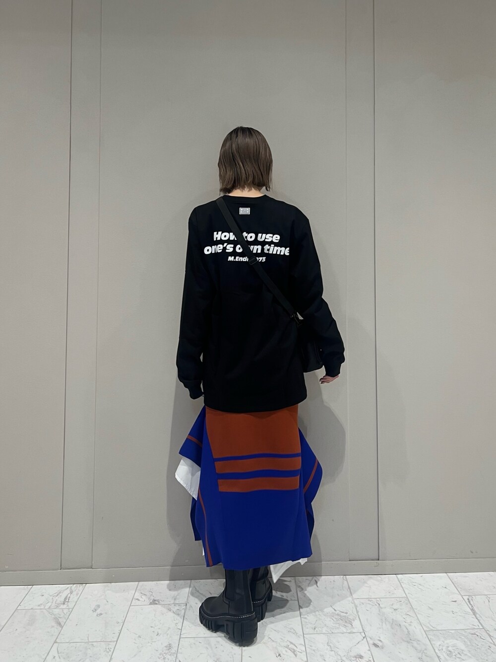 ブラック系のTシャツ/カットソー、ブラック系のショルダーバッグ、ブラック系のブーツを着用したレディースの秋コーディネートの2枚目の写真