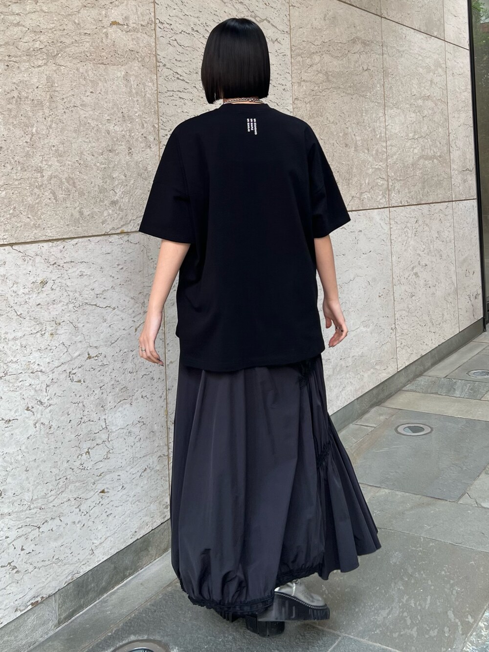 ブラック系のスカート、ブラック系のTシャツ/カットソー、シルバー系のブーツを着用したレディースの冬コーディネートの2枚目の写真