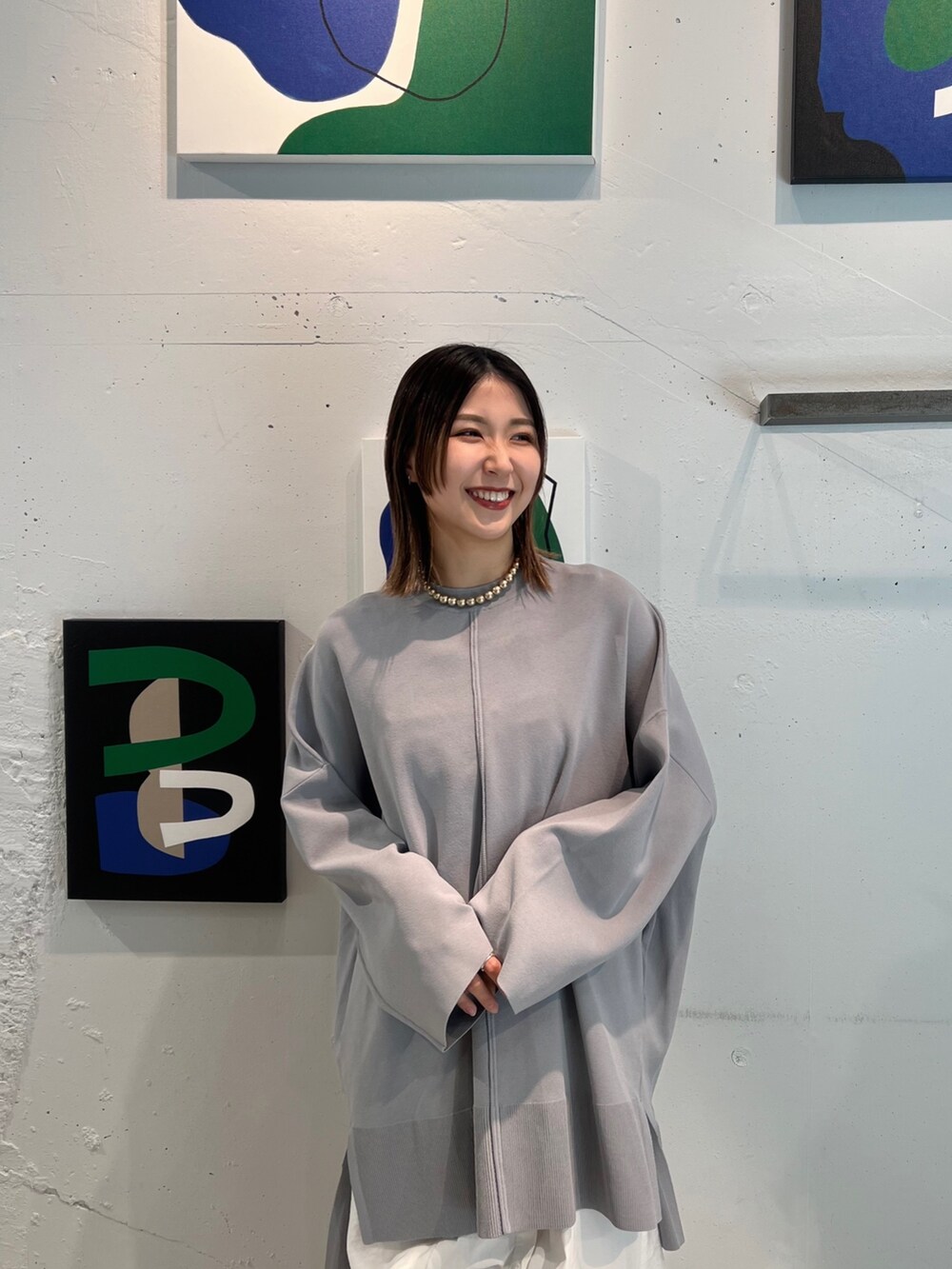 グレー系のニット/セーター、ホワイト系のワンピース、ブラック系のブーツを着用したレディースの冬コーディネートの4枚目の写真