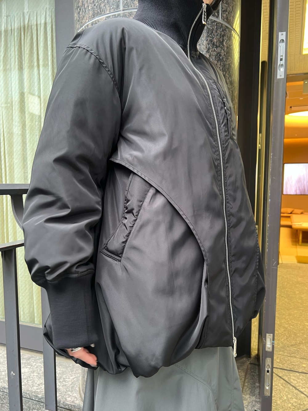 ブラック系のダウンジャケット/コート、グレー系のワンピース、ブラック系のブーツを着用したレディースの夏コーディネートの6枚目の写真