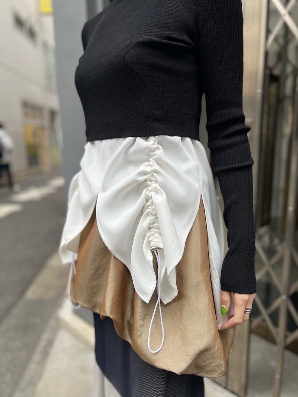 ブラック系のニット/セーター、ホワイト系のタンクトップ、イエロー系のスカートを着用したレディースの春コーディネートの4枚目の写真