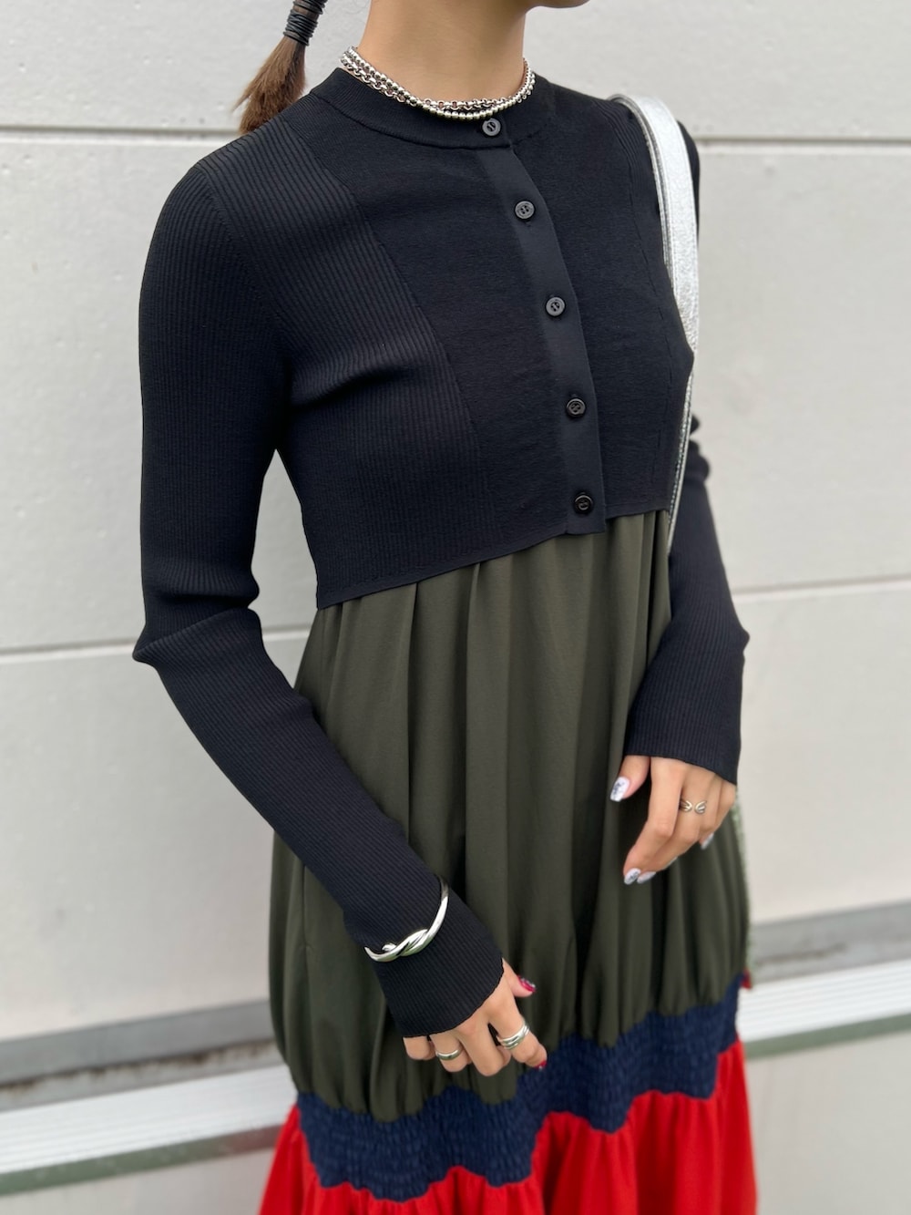 オレンジ系のワンピース、ブラック系のカーディガン/ボレロ、シルバー系のネックレスを着用したレディースの春コーディネートの4枚目の写真