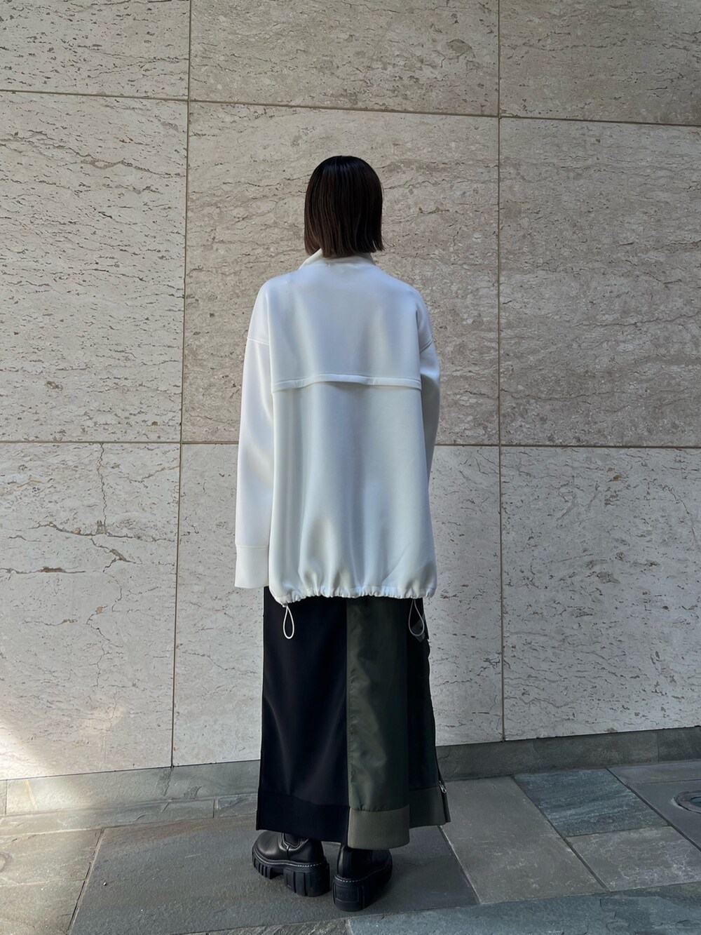 ブラック系のスカート、ホワイト系のスウェット、ブラック系のブーツを着用したレディースの秋コーディネートの2枚目の写真