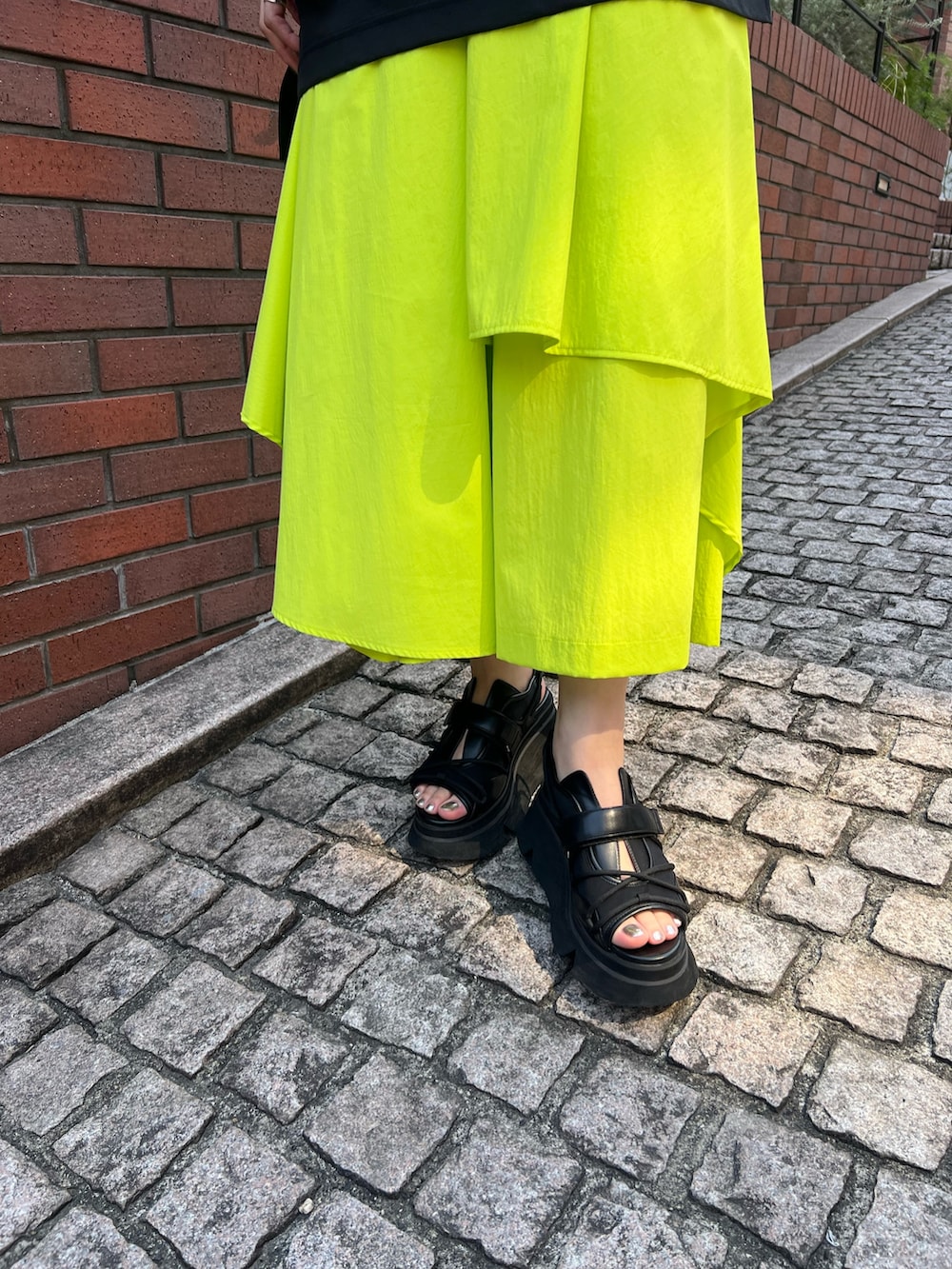 ブラック系のTシャツ/カットソー、イエロー系のその他パンツ、ブラック系のサンダルを着用したレディースの春コーディネートの8枚目の写真