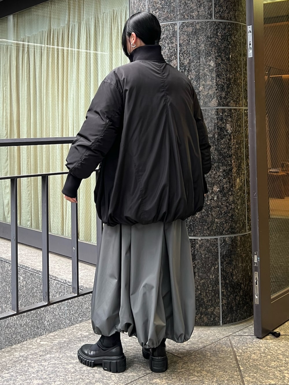 ブラック系のダウンジャケット/コート、グレー系のワンピース、ブラック系のブーツを着用したレディースの夏コーディネートの3枚目の写真