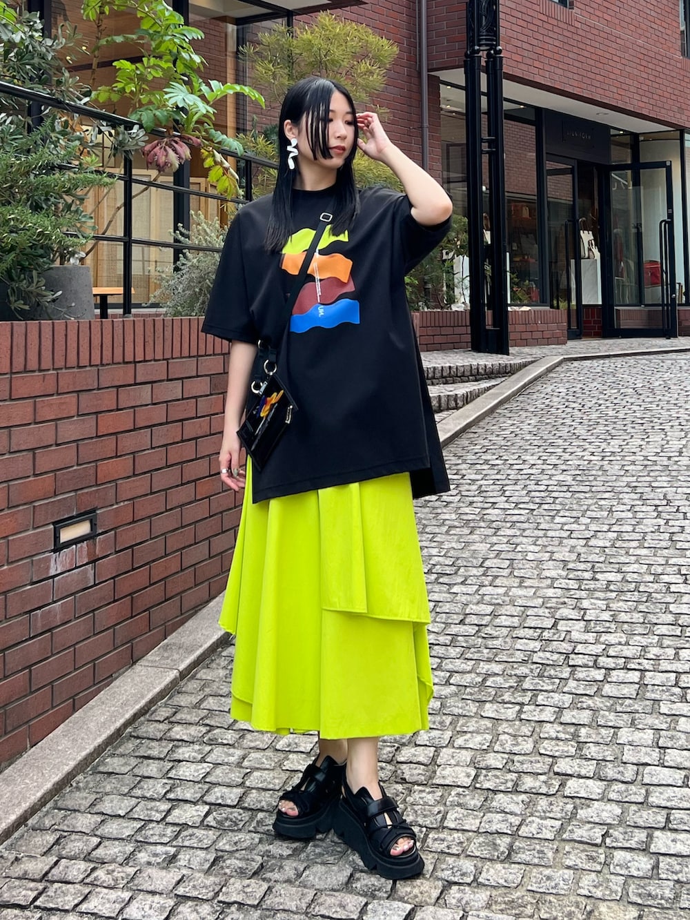 ブラック系のTシャツ/カットソー、イエロー系のその他パンツ、ブラック系のサンダルを着用したレディースの春コーディネートの3枚目の写真