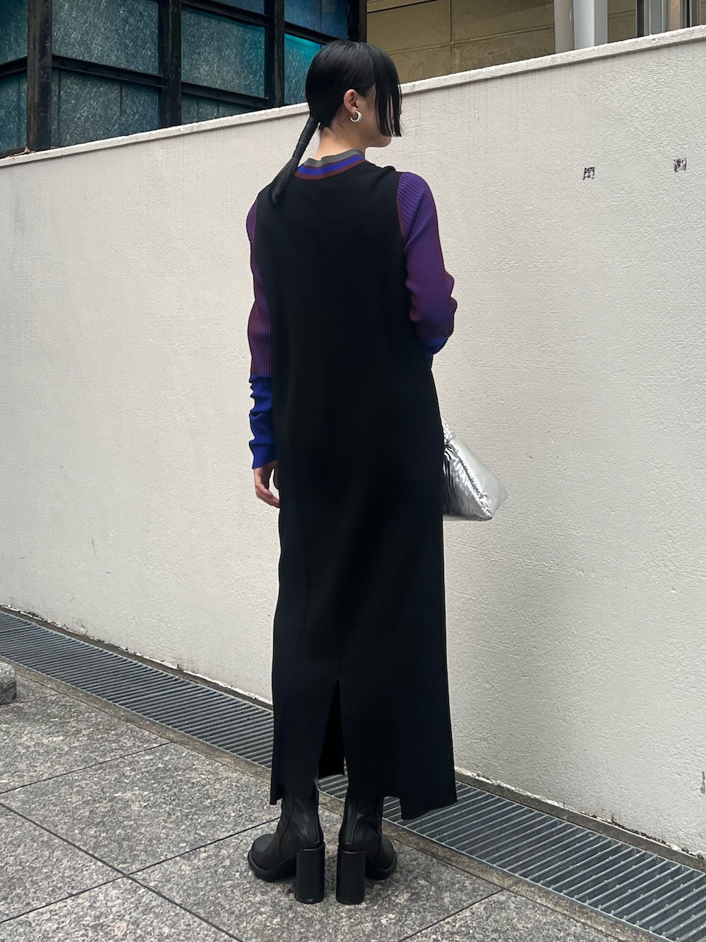 ブラック系のワンピース、シルバー系のハンドバッグ、ブラック系のブーツを着用したレディースの秋コーディネートの2枚目の写真