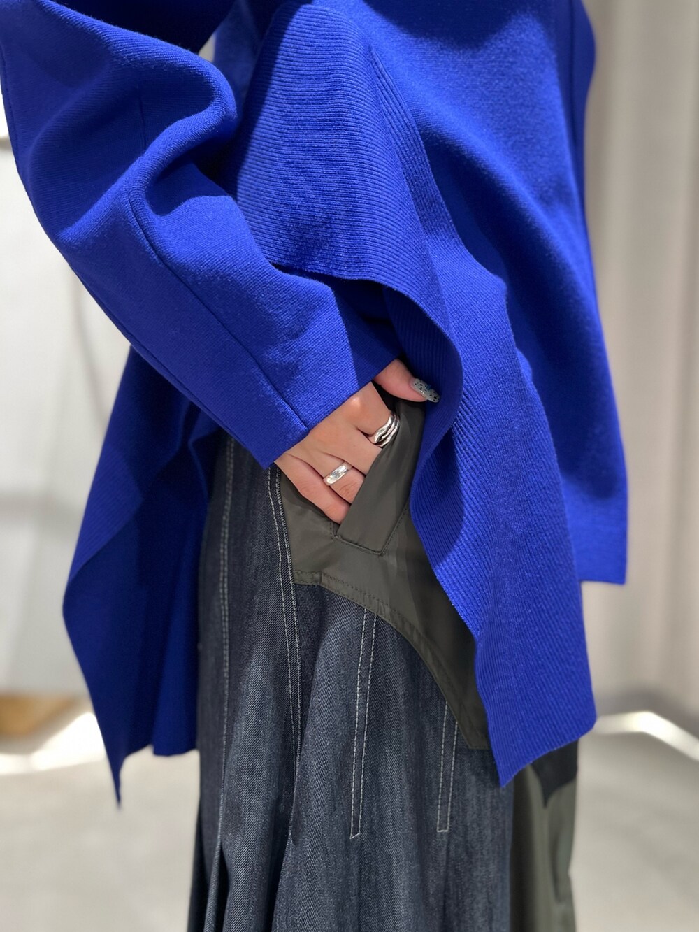 ブルー系のニット/セーター、ブラック系のスカート、ブラック系のブーツを着用したレディースの秋コーディネートの9枚目の写真