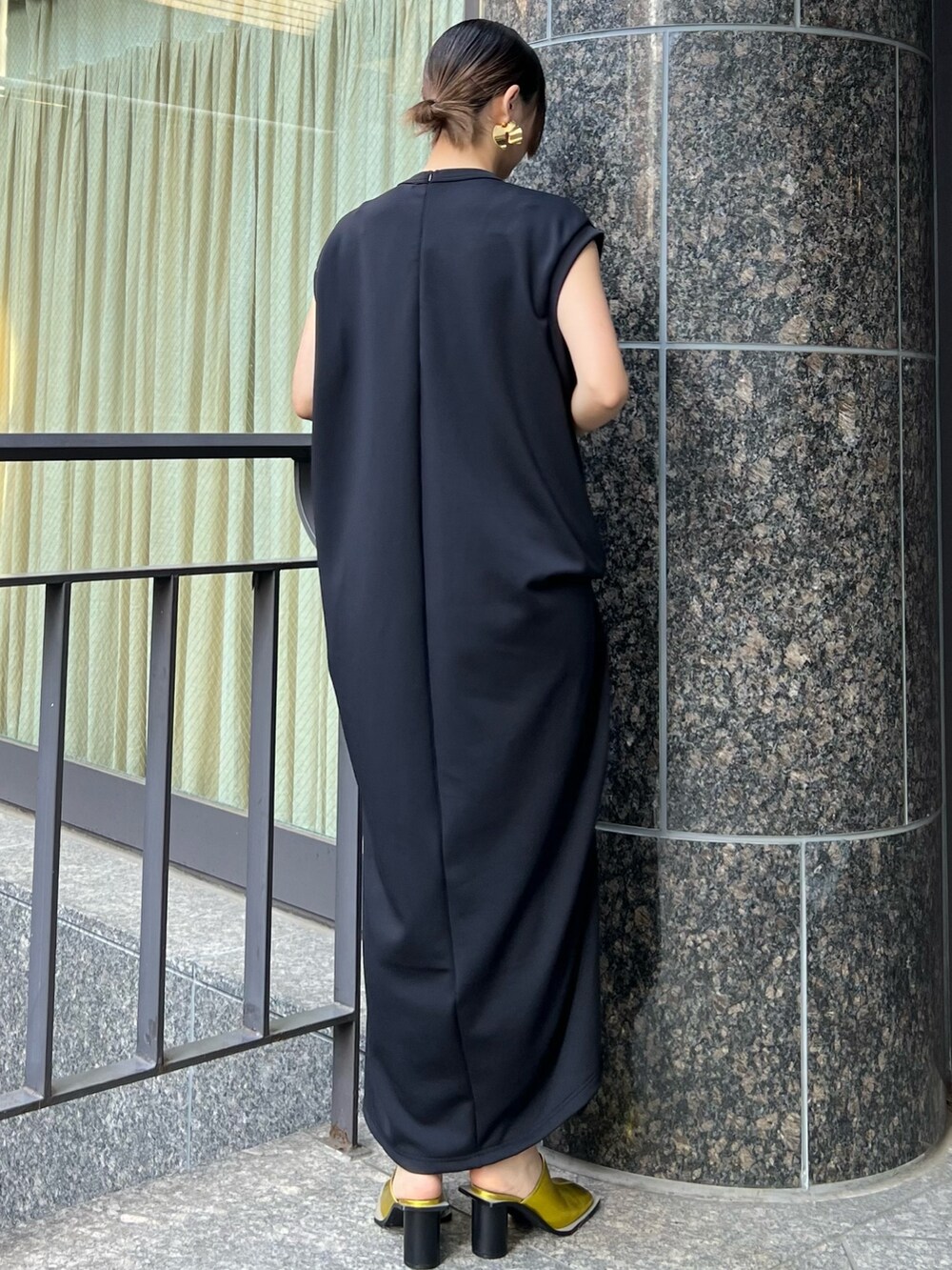 ブラック系のワンピース、ゴールド系のパンプス、ゴールド系のイヤリングを着用したレディースの冬コーディネートの2枚目の写真