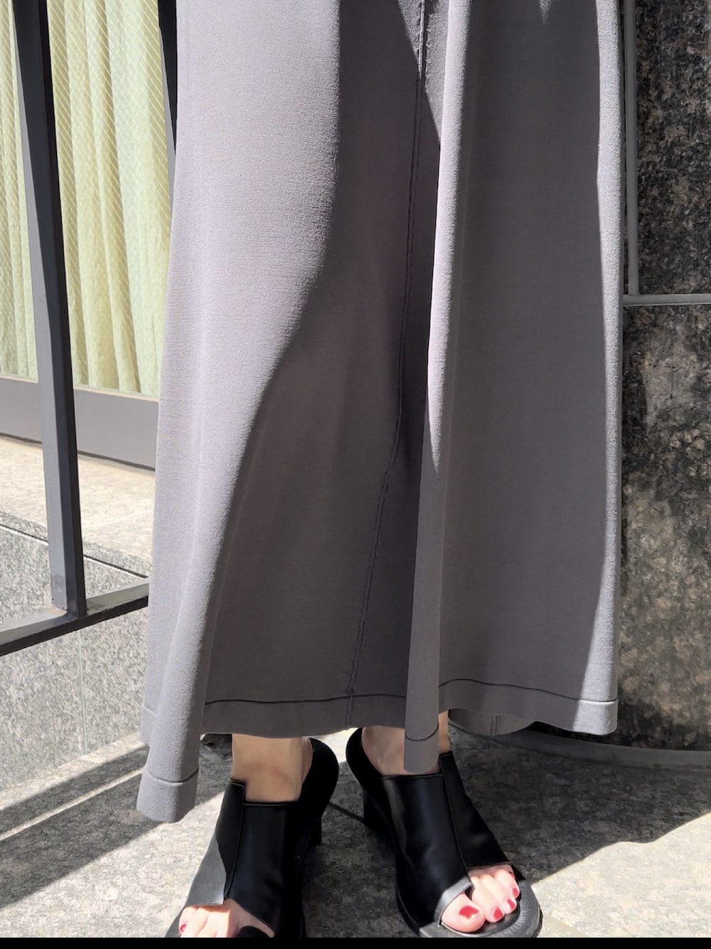 グレー系のワンピース、ブラック系のサンダル、シルバー系のネックレスを着用したレディースの春コーディネートの6枚目の写真