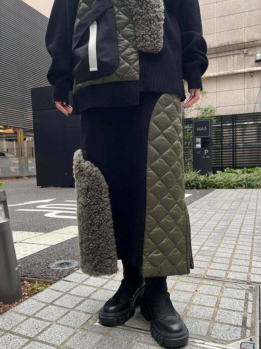 ブラック系のニット/セーター、ブラック系のスカート、ブラック系のブーツを着用したレディースの秋コーディネートの7枚目の写真