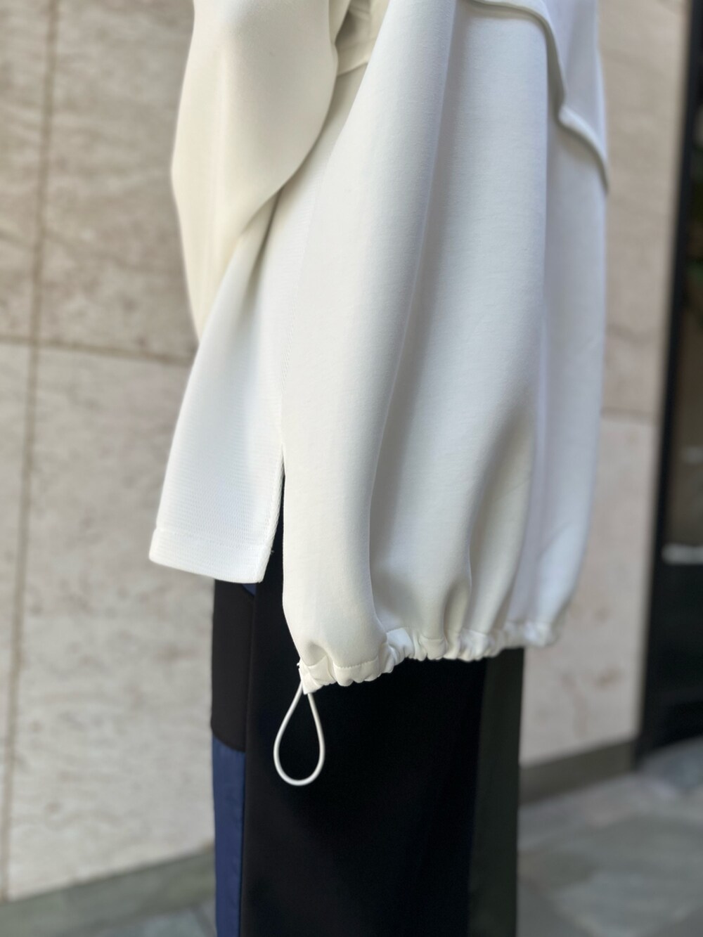 ブラック系のスカート、ホワイト系のスウェット、ブラック系のブーツを着用したレディースの秋コーディネートの7枚目の写真