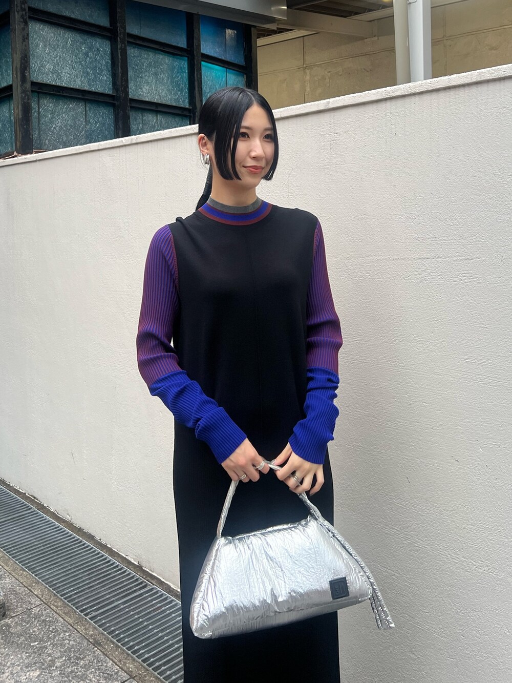 ブラック系のワンピース、シルバー系のハンドバッグ、ブラック系のブーツを着用したレディースの秋コーディネートの3枚目の写真