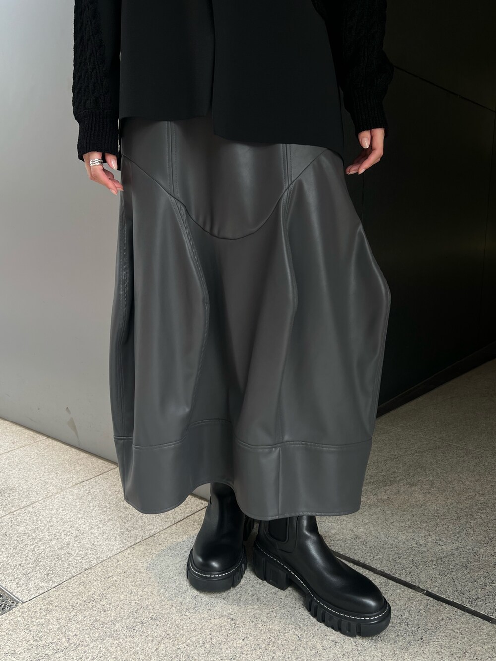 ブラック系のニット/セーター、グレー系のスカート、ブラック系のブーツを着用したレディースの秋コーディネートの7枚目の写真