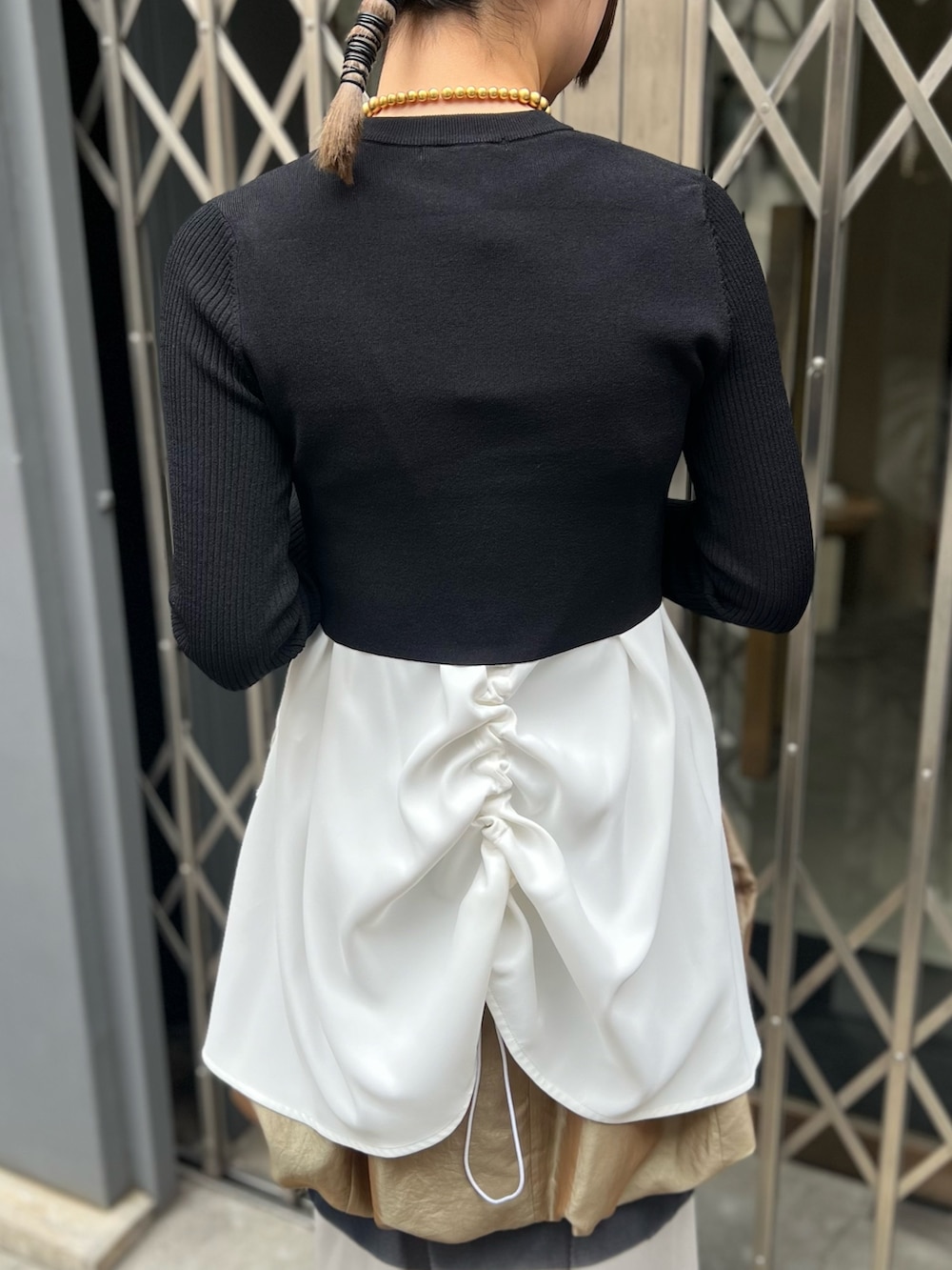 ブラック系のニット/セーター、ホワイト系のタンクトップ、イエロー系のスカートを着用したレディースの春コーディネートの7枚目の写真