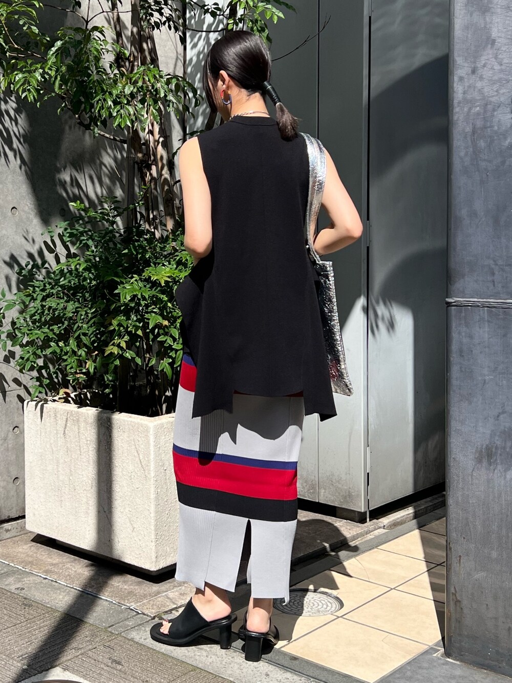 ブラック系のニット/セーター、ブラック系のスカート、シルバー系のトートバッグを着用したレディースの夏コーディネートの2枚目の写真