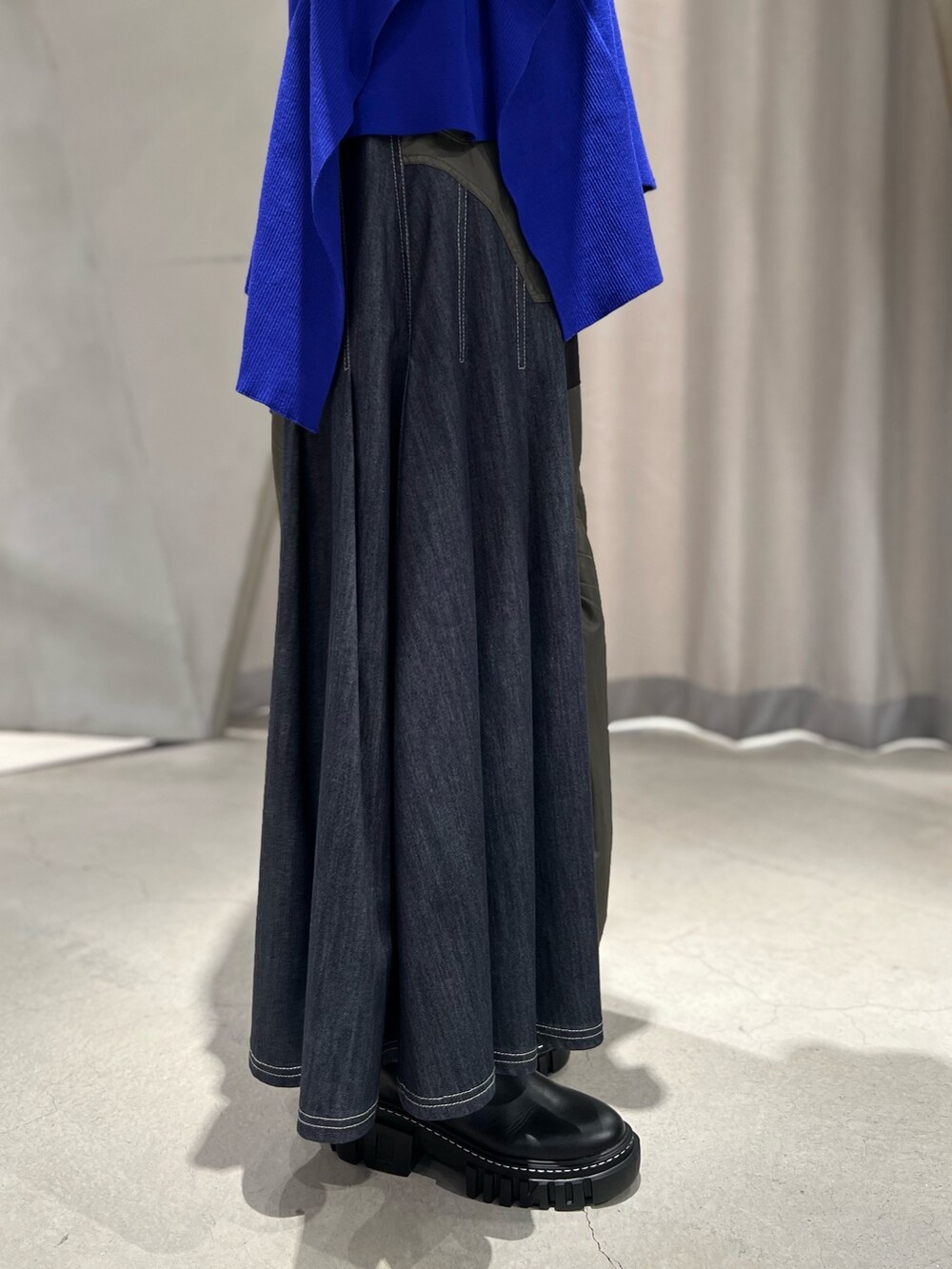 ブルー系のニット/セーター、ブラック系のスカート、ブラック系のブーツを着用したレディースの秋コーディネートの8枚目の写真