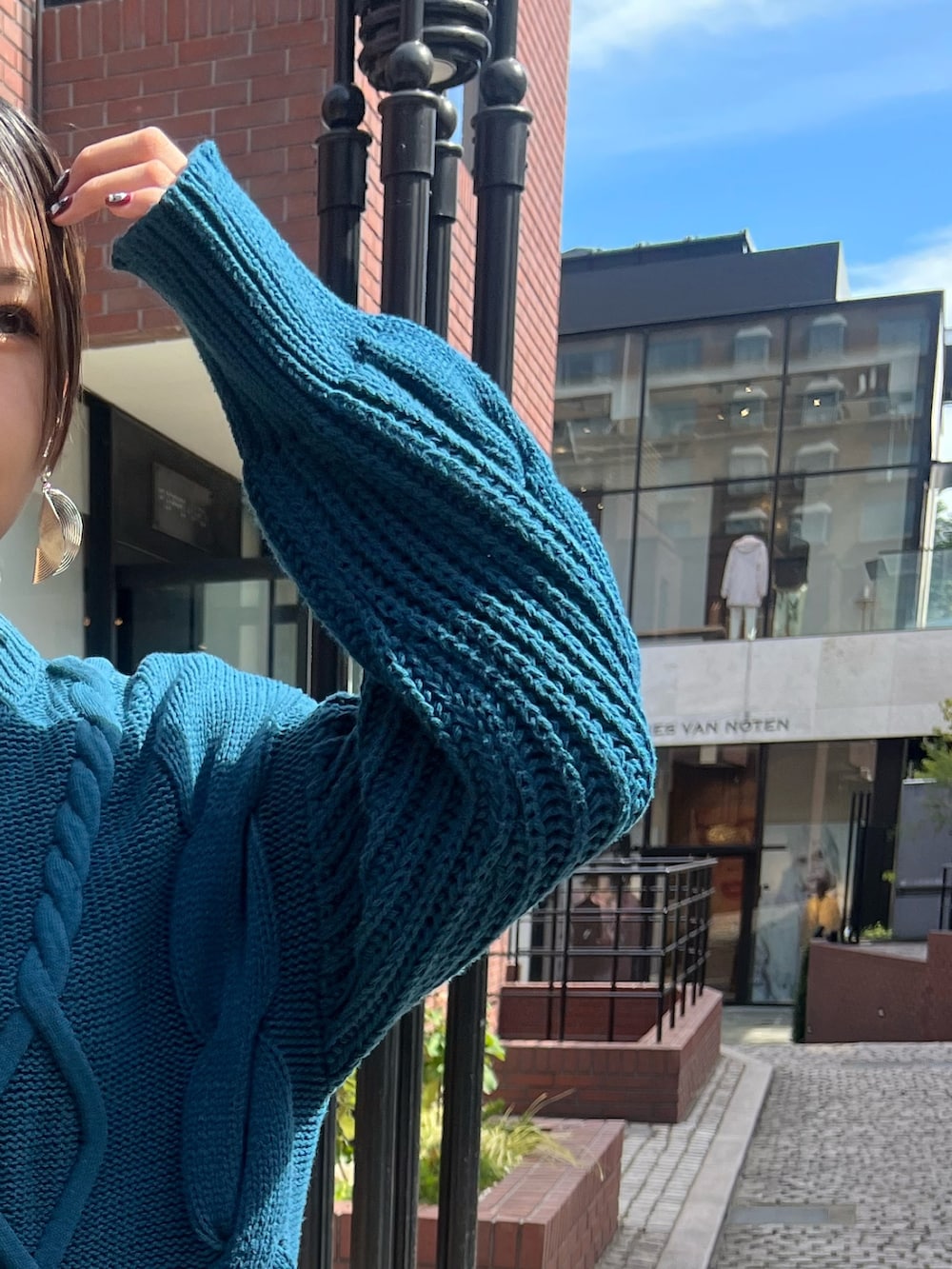 ブルー系のワンピース、ブラック系のブーツ、シルバー系のイヤリングを着用したレディースの秋コーディネートの7枚目の写真