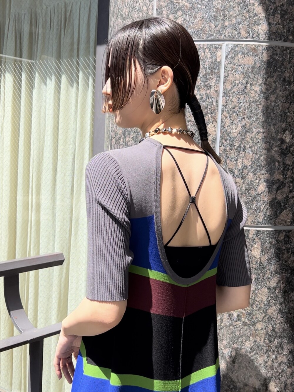 グレー系のワンピース、ブラック系のサンダル、シルバー系のネックレスを着用したレディースの春コーディネートの5枚目の写真