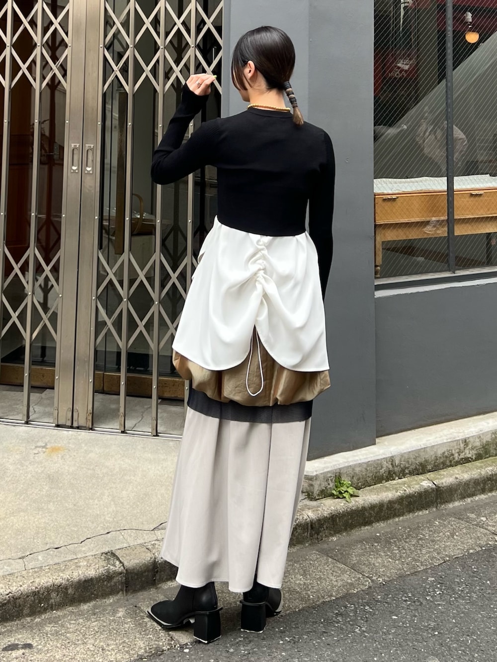 ブラック系のニット/セーター、ホワイト系のタンクトップ、イエロー系のスカートを着用したレディースの春コーディネートの2枚目の写真