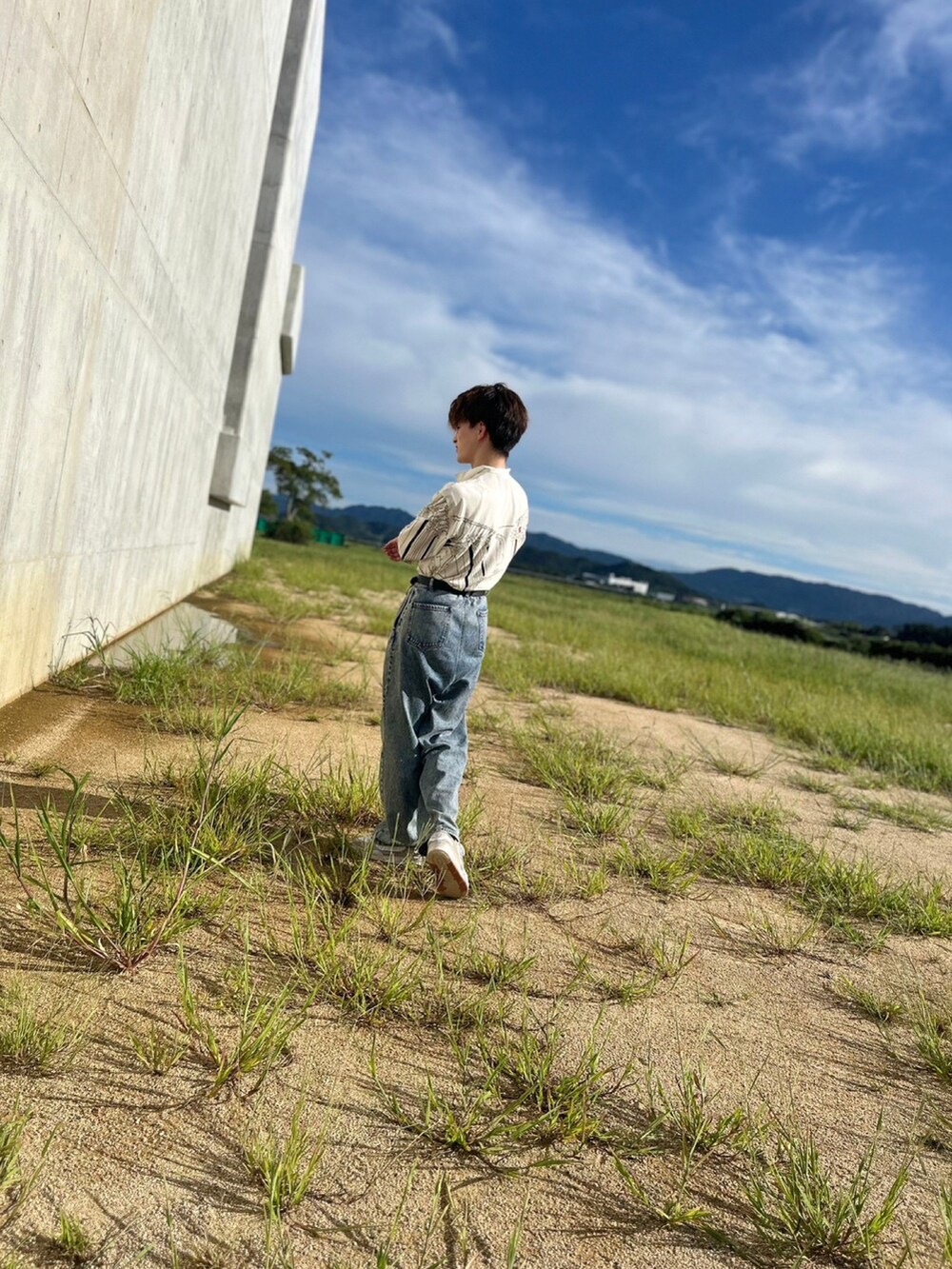 ブルー系のデニムパンツ、ベージュ系のスニーカー、ブラック系のベルトを着用したメンズの秋コーディネートの3枚目の写真