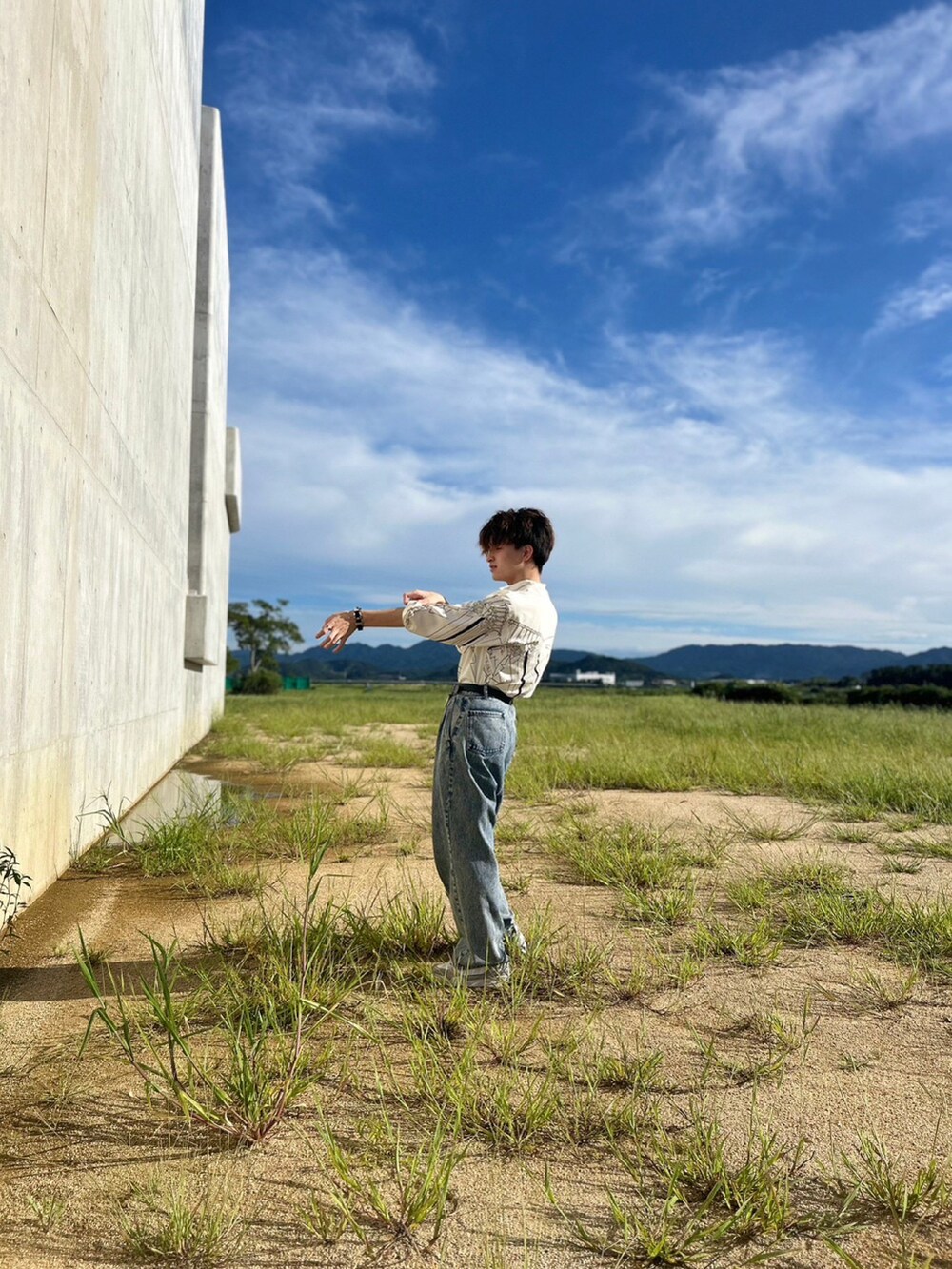 ブルー系のデニムパンツ、ベージュ系のスニーカー、ブラック系のベルトを着用したメンズの秋コーディネートの4枚目の写真