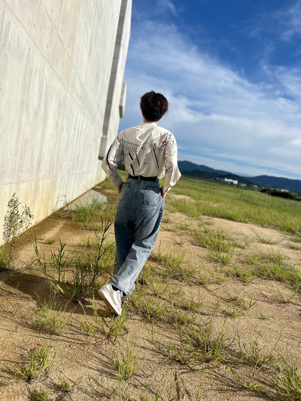 ブルー系のデニムパンツ、ベージュ系のスニーカー、ブラック系のベルトを着用したメンズの秋コーディネートの2枚目の写真