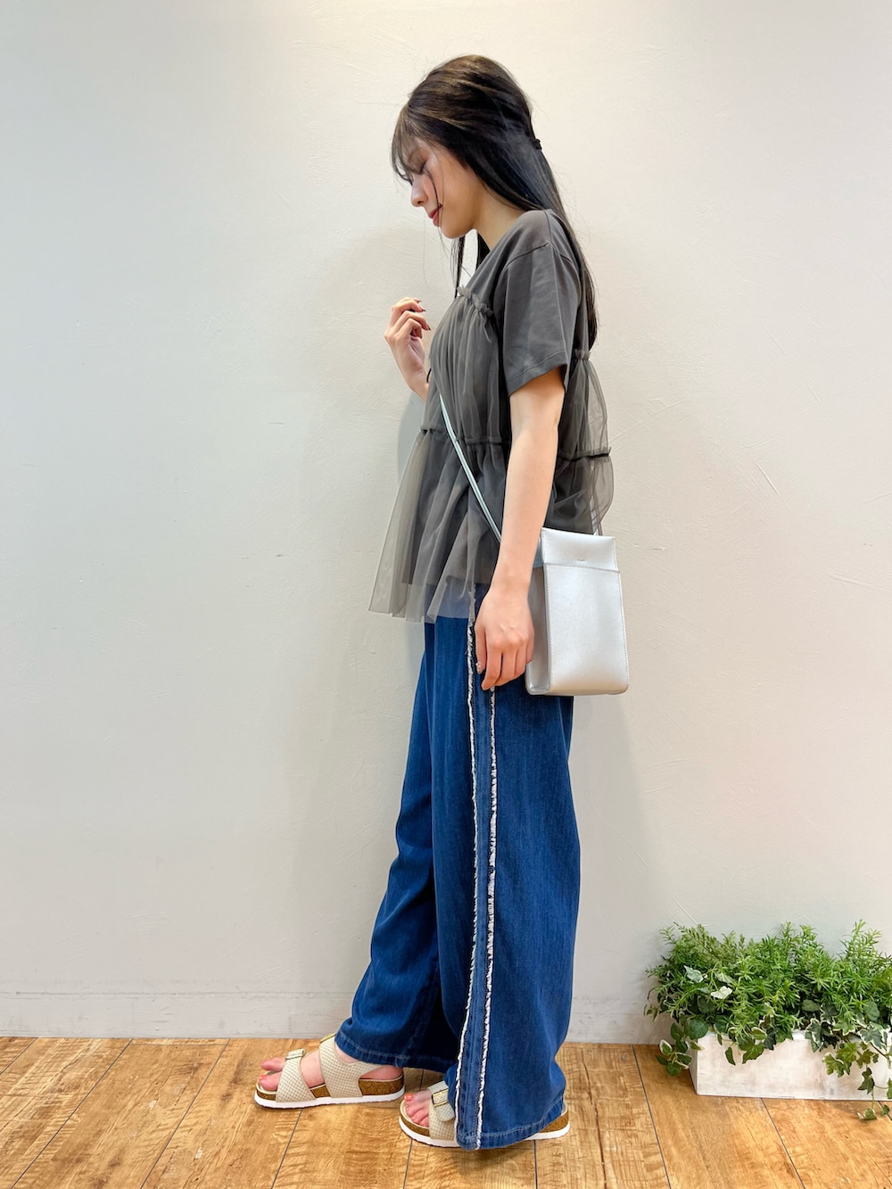 グレー系のTシャツ/カットソー、ブルー系のデニムパンツ、シルバー系のショルダーバッグを着用したレディースの夏コーディネートの2枚目の写真