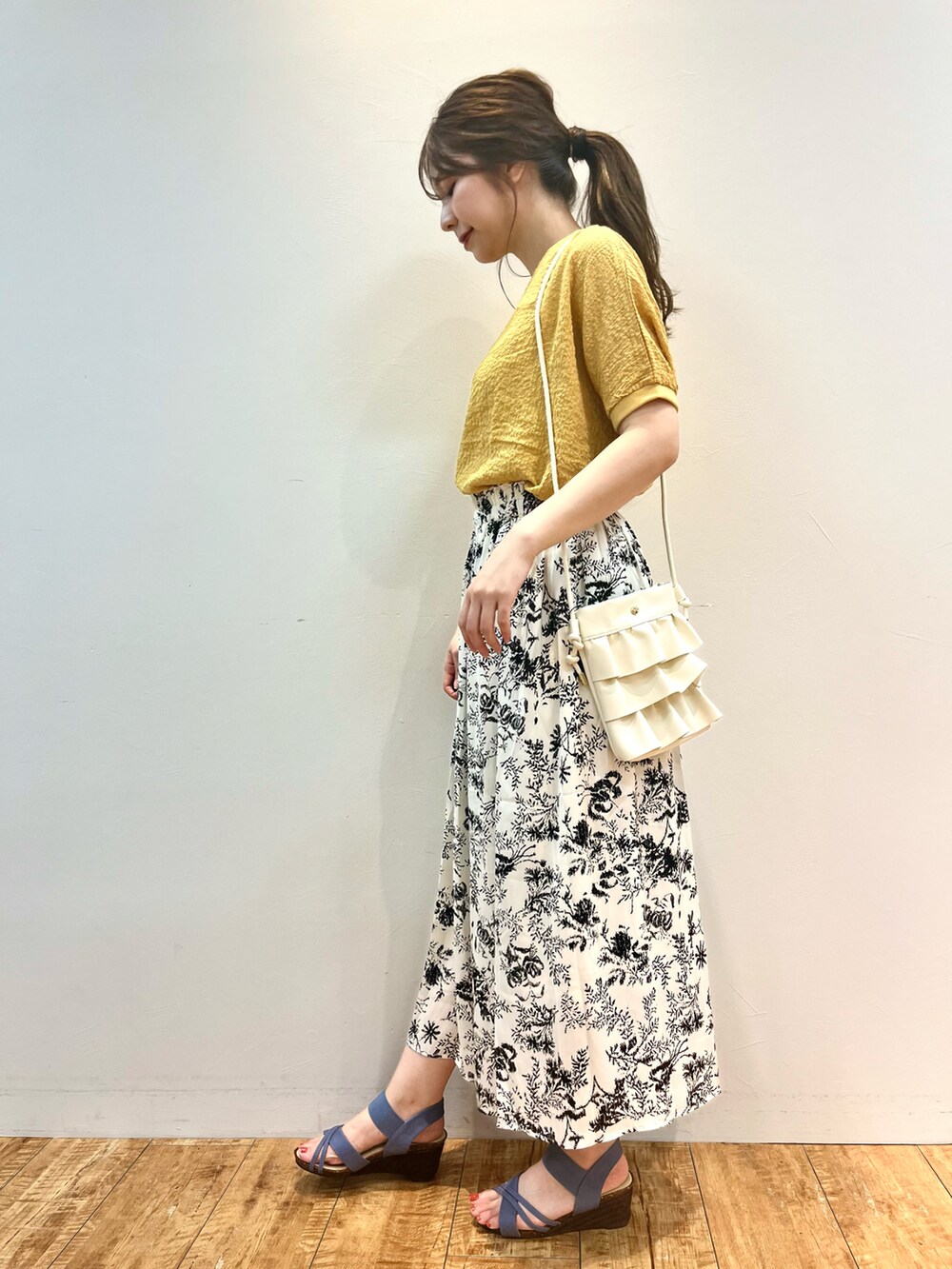 イエロー系のシャツ/ブラウス、ホワイト系のショルダーバッグ、ベージュ系のスカートを着用したレディースの夏コーディネートの2枚目の写真