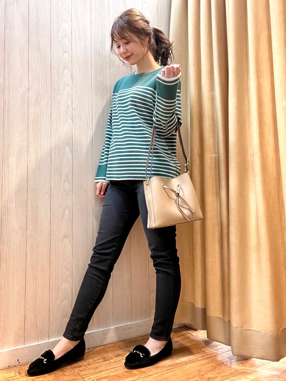 グリーン系のニット/セーター、ブラック系のデニムパンツ、ベージュ系のショルダーバッグを着用したレディースの冬コーディネートの2枚目の写真