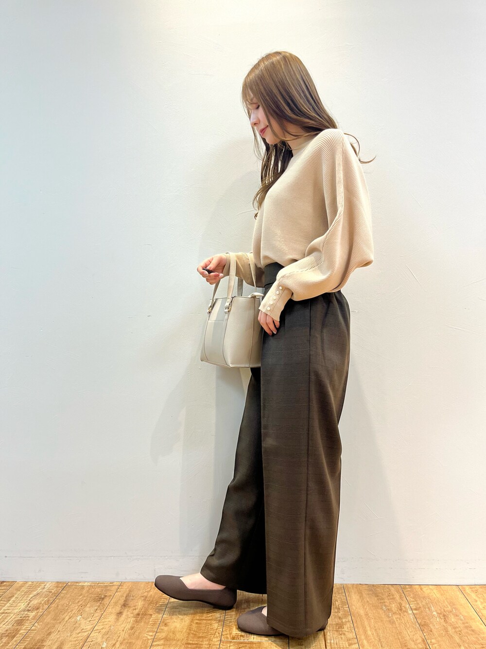 ベージュ系のニット/セーター、ブラウン系のその他パンツ、グレー系のトートバッグを着用したレディースの冬コーディネートの2枚目の写真
