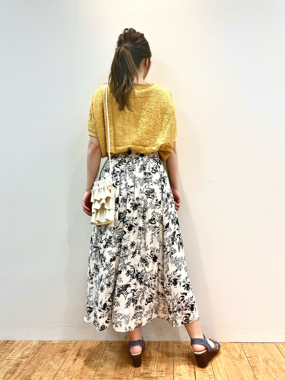 イエロー系のシャツ/ブラウス、ホワイト系のショルダーバッグ、ベージュ系のスカートを着用したレディースの夏コーディネートの3枚目の写真