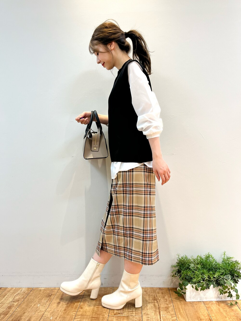 ブラック系のその他トップス、ベージュ系のスカート、ベージュ系のハンドバッグを着用したレディースの秋コーディネートの2枚目の写真