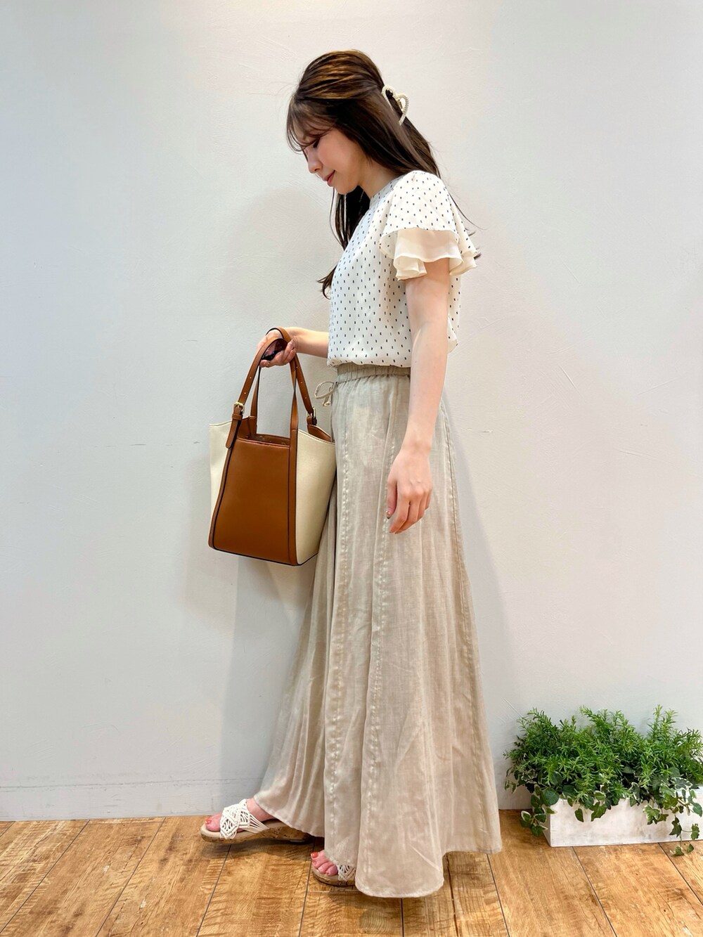 ホワイト系のシャツ/ブラウス、ベージュ系のスカート、イエロー系のトートバッグを着用したレディースの夏コーディネートの2枚目の写真