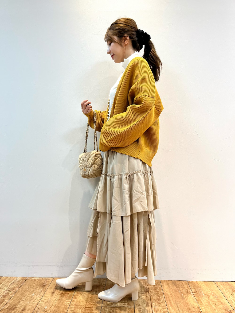 イエロー系のカーディガン/ボレロ、ホワイト系のTシャツ/カットソー、ベージュ系のスカートを着用したレディースの秋コーディネートの2枚目の写真