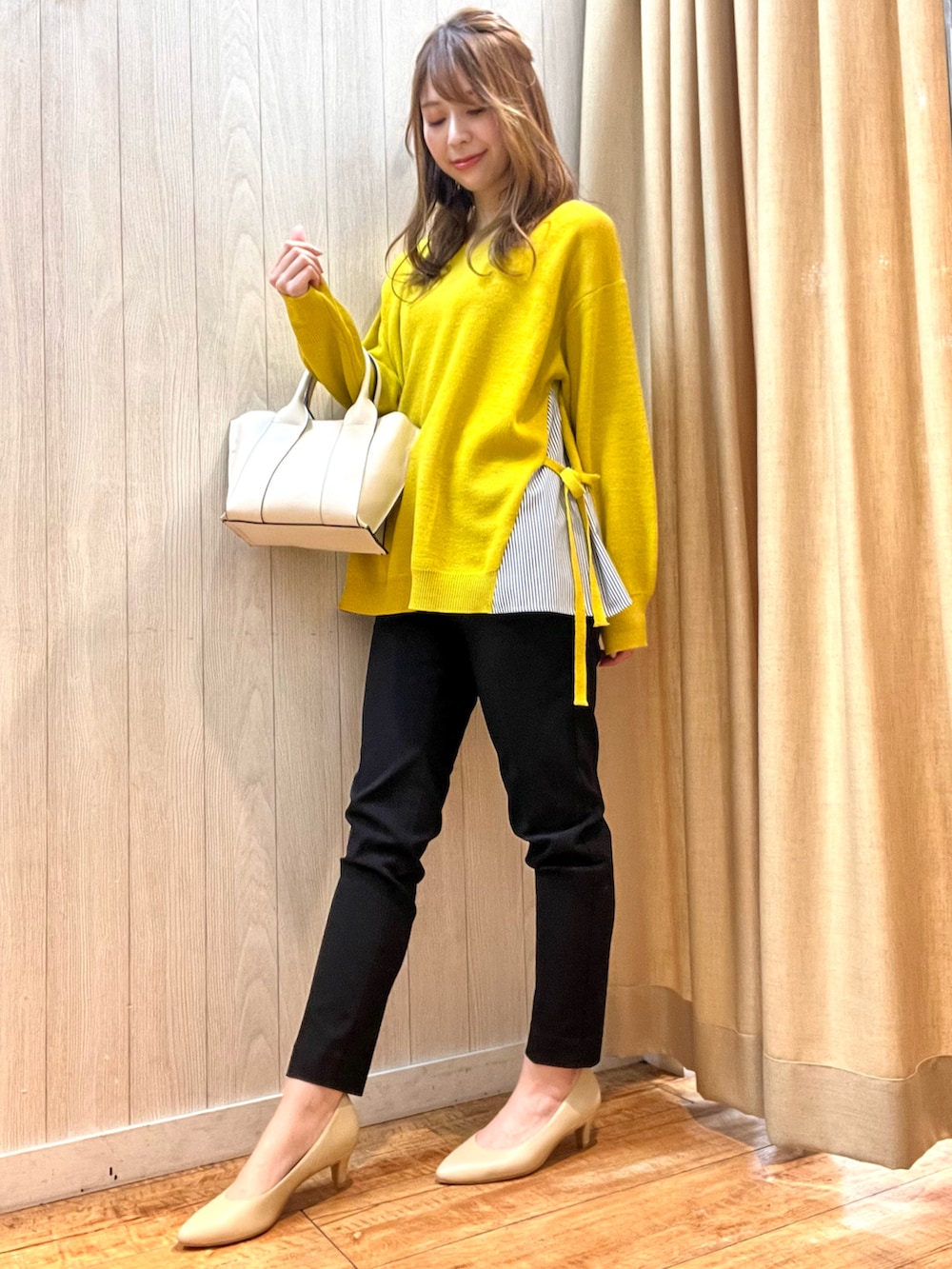 イエロー系のニット/セーター、ホワイト系のトートバッグ、ブラック系のその他パンツを着用したレディースの冬コーディネートの2枚目の写真
