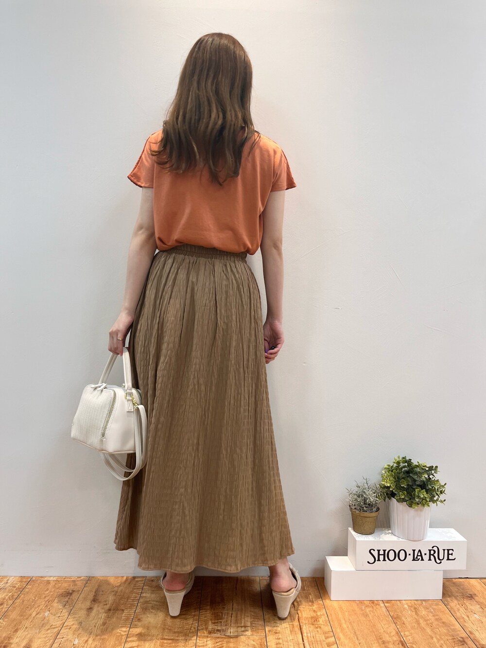 オレンジ系のTシャツ/カットソー、イエロー系のスカート、ホワイト系のショルダーバッグを着用したレディースの夏コーディネートの3枚目の写真