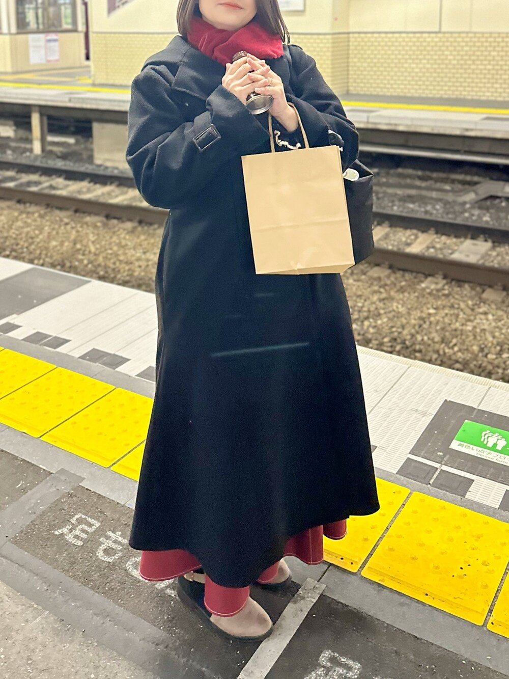 ベージュ系のブーツ、レッド系のスカート、ブラック系のトートバッグを着用したレディースの冬コーディネートの2枚目の写真