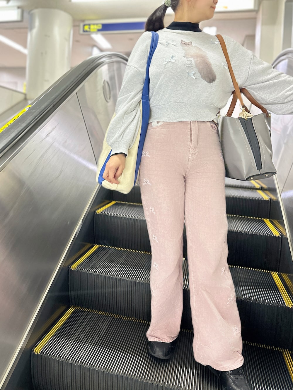 ホワイト系のスウェット、ブラック系のトップス、ピンク系のデニムパンツを着用したレディースの秋コーディネートの2枚目の写真