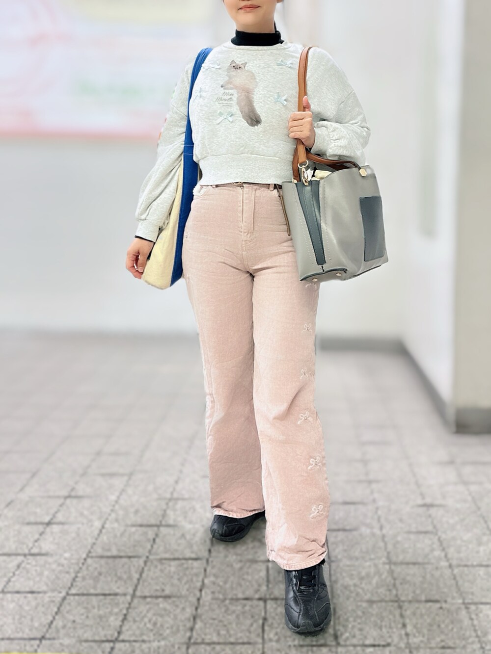 ホワイト系のスウェット、ブラック系のトップス、ピンク系のデニムパンツを着用したレディースの秋コーディネートの3枚目の写真