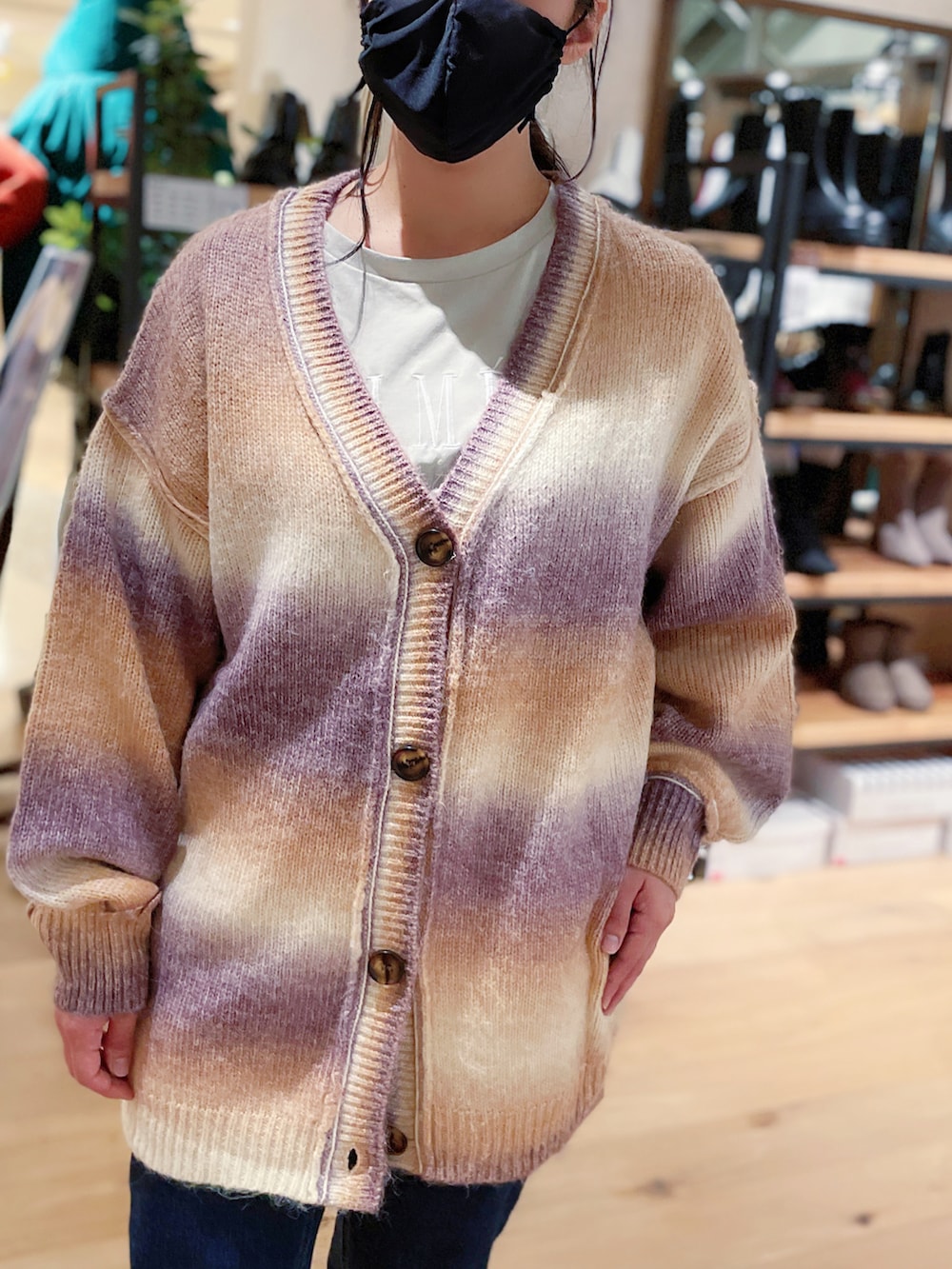 グレー系のTシャツ/カットソー、オレンジ系のカーディガン/ボレロ、ブルー系のデニムパンツを着用したレディースの秋コーディネートの2枚目の写真