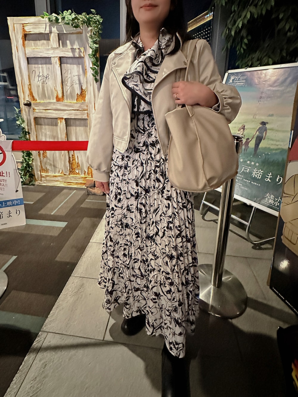 ブラック系のブーツ、ベージュ系のトートバッグ、ホワイト系のワンピースを着用したレディースの春コーディネートの2枚目の写真