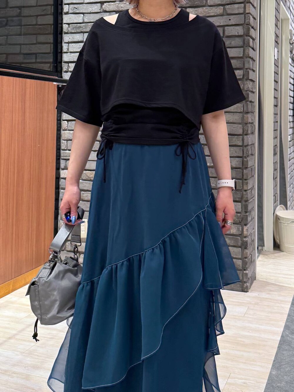 グリーン系のスカート、ブラック系のサンダル、ベージュ系のショルダーバッグを着用したレディースの春コーディネートの4枚目の写真